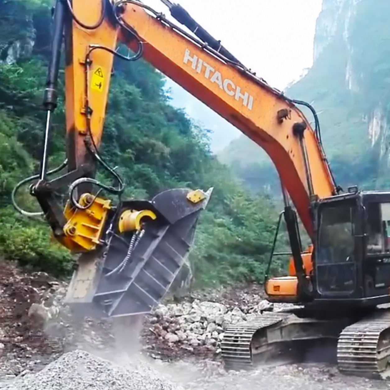 Hitachi excavator with a large rotating tilt bucket working at a high tilt angle
